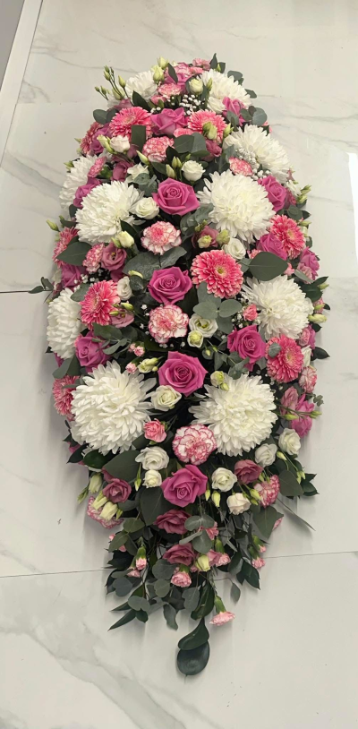 Pink Serenity Spray - A beautifully crafted full-length casket spray designed in a graceful palette of soft pink, crisp white, and silvery green foliage. Rich in texture and elegantly arranged with flowing lines, this heartfelt tribute symbolises love, peace, remembrance, and cherished memories. Created to honour the life of a loved one with dignity and compassion, it provides a comforting and timeless floral tribute, making it a fitting centrepiece for funeral and memorial services.