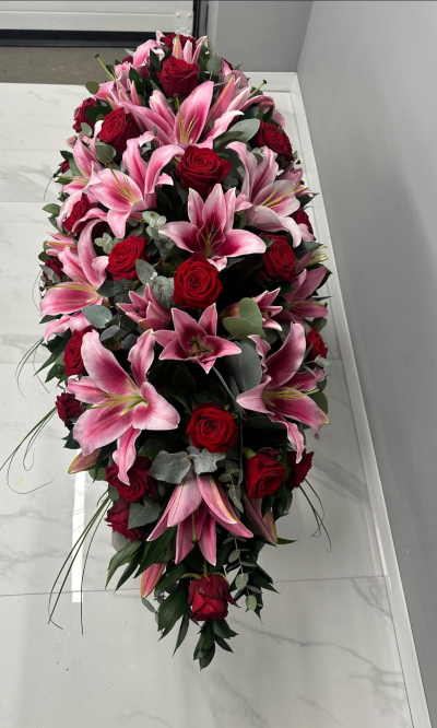 Everlasting Love Spray - A luxurious full-length casket spray designed in a rich palette of romantic crimson, soft blush pink, and silvery green foliage. Expertly arranged with elegant flowing lines and abundant textures, this heartfelt tribute symbolises enduring love, cherished memories, and deep respect. Created to honour the life of a beloved family member or friend, this timeless arrangement offers a beautiful expression of sympathy, comfort, and remembrance, providing a striking and dignified centrepiece for funeral and memorial services.