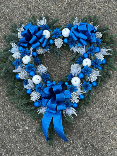 Sapphire Heart - Celebrate the season with the striking beauty of the Sapphire Heart Christmas Wreath. Handcrafted in a heart-shaped design using fresh evergreen foliage, this elegant wreath is adorned with shimmering blue and white decorations, frosted seasonal accents, decorative ornaments, and luxurious satin bows. Symbolising love, remembrance, and festive joy, this unique wreath is a stunning way to decorate your home or honour someone special during the Christmas season.