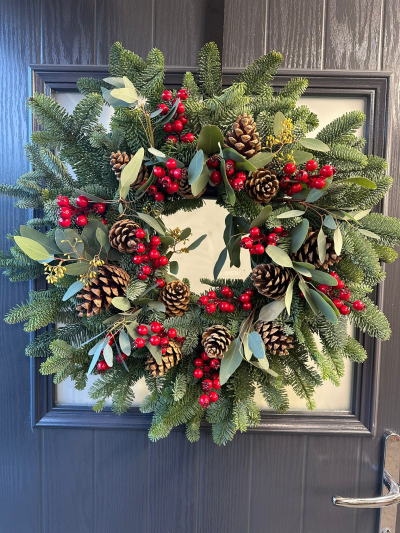 Woodland Berry - Celebrate the beauty of a traditional Christmas with the Woodland Berry Christmas Wreath. Handcrafted with fresh evergreen foliage, this timeless design is beautifully accented with natural pinecones, vibrant red berries, and silvery-green foliage for a classic woodland look. Rich in texture and festive charm, this elegant wreath brings a warm, welcoming touch to your front door and makes a stunning seasonal decoration throughout the holiday season.